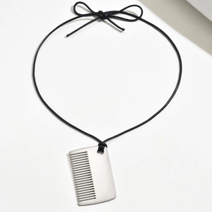 Détail macro du pendentif peigne argenté mat avec un élégant cordon noir tissé