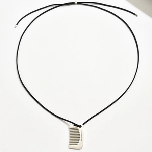 Détail du pendentif peigne argenté avec gravure laser sur un cordon tressé noir