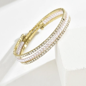 Dettaglio del bracciale dorato multistrato con perle bianche e strass scintillanti