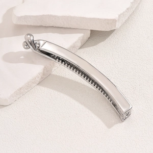 Sleek silver metal banana hair clip with teeth on a minimalist stone background