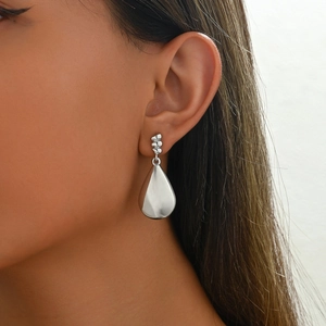 Sleek silver teardrop dangle earrings with irregular textured studs on a female model