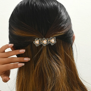 Daisy petal hair clip with black gold enamel and pearls on dark brown wavy hair