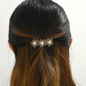 Detail view of vintage daisy hair clip with black enamel petals and white pearls on hair