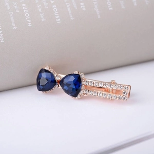 Détail macro d'une barrette en or rose avec cœurs en cristal bleu et strass pavés