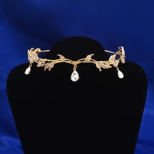 Tiara nuziale dorata con design a foglie e cristalli a goccia appesi su un supporto