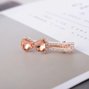 Gros plan de la pince à cheveux noeud en or rose sertie de strass champagne brillants
