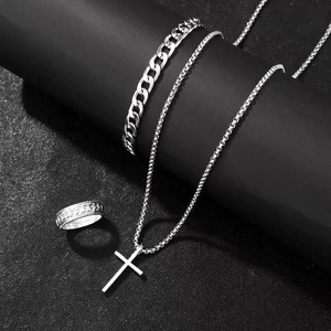 Detail view of silver cross pendant necklace, Cuban bracelet, and textured ring set