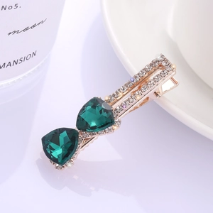 Détail d'une épingle à cheveux dorée avec grandes pierres émeraude et zircons blancs