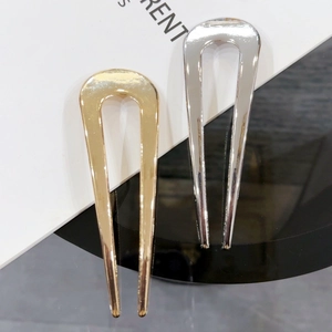 Detail view of U-shaped metal hair pins in polished gold and silver finishes
