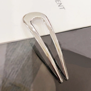 Detail view of the polished silver U-shaped hair pin showing its sleek metallic finish