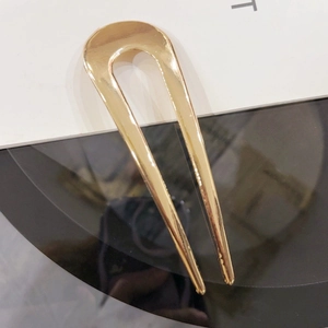 Detailed close-up of a minimalist U-shaped gold alloy hair pin with a polished metallic finish