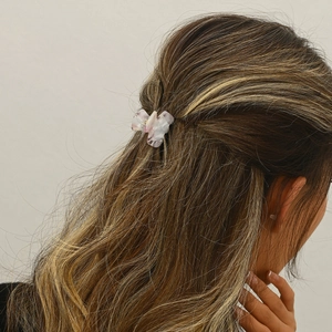 Close-up of a small acetate marble hair claw clip worn on a woman's half-up hairstyle