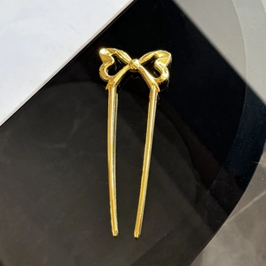 Detail einer goldenen Haarspange in Schleifenform mit polierter Oberfläche und U-förmigem Design