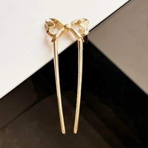 Eleganter goldener U-förmiger Haarnadel mit stilvollem hohlem Schleifendesign auf Kontrast
