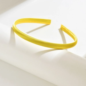 Close-up of bright yellow satin-covered U-shaped headband showing fine inner stitching detail