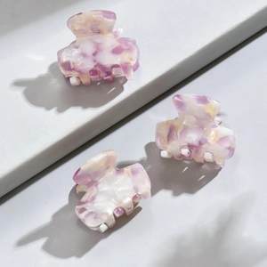 Three mini leopard acetate hair claws in purple marble pattern on a geometric background