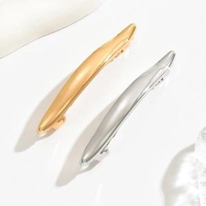 Minimalist metallic spring hair clips in gold and silver finish on white background