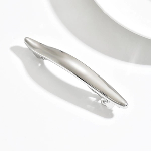 Macro shot of polished silver metal hair clip with a sleek curved spring design