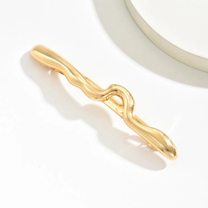 Vue détaillée d'une barrette à cheveux dorée ondulée avec finition polie brillante