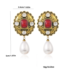 Boucles d'oreilles vintage style palais avec pierre rouge et perles sur fond blanc