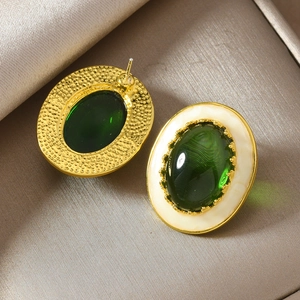 Boucles d'oreilles vintage dorées avec pierres vert émeraude et bord blanc sur soie champagne