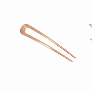 Dettaglio di forcina per capelli in metallo oro rosa a forma di U con finitura testurizzata