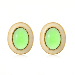 Détail de boucles d'oreilles dorées avec pierres vertes ovales et bordure perlée