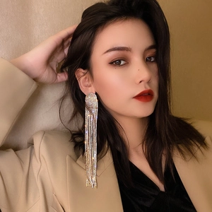 Elegant long gold tassel earrings with shimmering rhinestones worn by a model in a suit