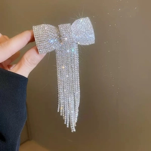 Détail d'une pince à cheveux nœud en strass argentés avec de longues chaînes à pompons