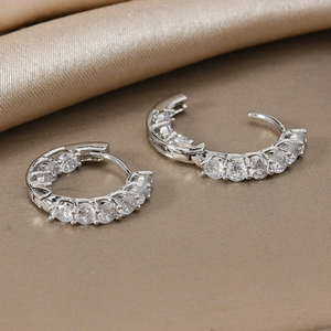 Eleganti orecchini a cerchio in argento con diamanti tondi scintillanti su seta champagne