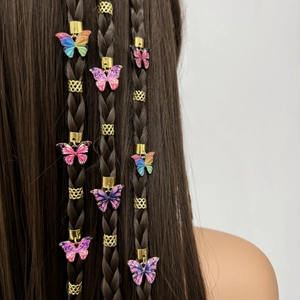 Dettaglio di pendenti a farfalla colorati su anelli di metallo dorato per capelli boho