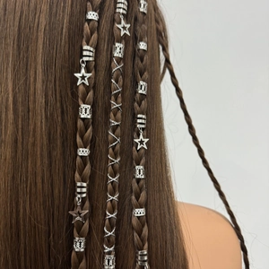Detailed close-up of silver hollow hair rings and star pendants on braided brown hair