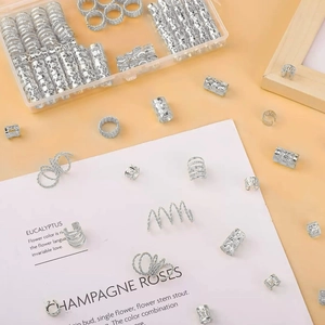 Silver metal dreadlock cuffs and hair coils displayed in a clear plastic storage box