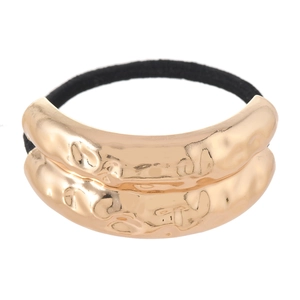 Detailed macro view of textured gold liquid metal hair tie with black elastic band