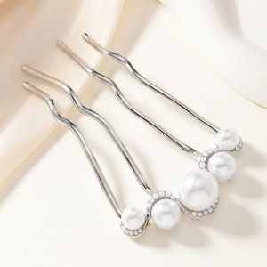 Detail view of silver U-shaped hair pin with elegant white pearls on satin background