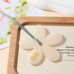 Collier avec pendentif fleur aux pétales blancs et cordon vert sur plateau en bois