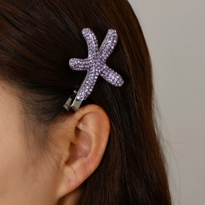 Gros plan d'une pince à cheveux étoile de mer avec strass violets sur cheveux bruns