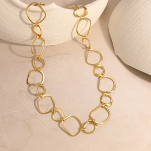 Macro detail of interlocking gold oval links of the necklace on a ceramic texture