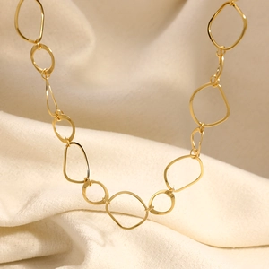 Detailed macro view of 18K gold plated interlocking geometric links on soft fabric