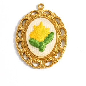 Macro shot of gold-plated oval pendant with intricate embroidery and floral lace edges
