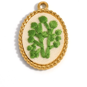 Detailed view of oval floral pendant with milgrain edge and delicate green leaf embroidery