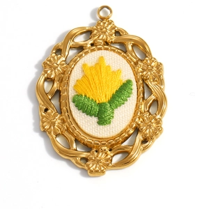 Detail of vintage 18K gold plated oval flower pendant with handmade floral embroidery