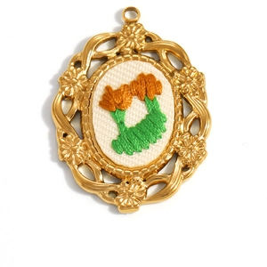 Detailed close-up of 18K gold plated oval pendant with hand-embroidered floral patterns