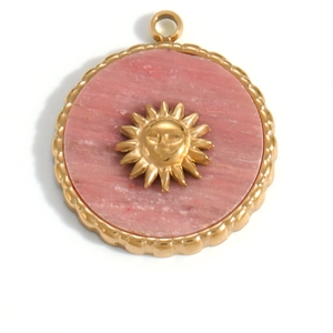 Detailed close-up of a 18K gold plated sun relief pendant with pink stone and scalloped edge