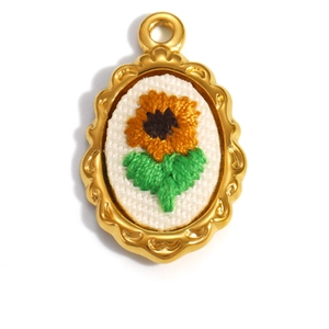 Detailed macro view of 18K gold plated oval pendant with embroidered sunflower design