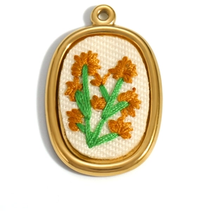 Detailed macro view of an oval 18K gold-plated pendant with hand-stitched floral embroidery