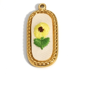 Detail of oval 18K gold plated pendant with floral embroidery and scalloped metal edges