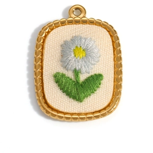 Macro detail of oval floral embroidery pendant with 18K gold plated textured metal frame
