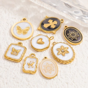 Detailansicht von Vintage-Anhängern aus 18k Gold mit Emaille-Schmetterlings- und Kreuzmotiven