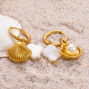 Détail de boucles d'oreilles asymétriques en or 18 carats avec coquillages et perles marines